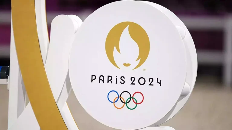 The official logo of the Paris 2024 Olympic Games, featuring a gold flame within a circle and the Olympic rings below.